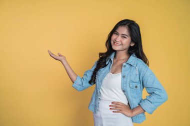 El hareketi yapan Asyalı bir kız izole bir arka planda bir şey sunuyor.