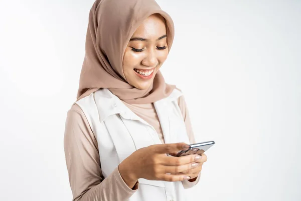 Aziatische vrouw in hijab glimlachen terwijl met behulp van een mobiele telefoon — Stockfoto