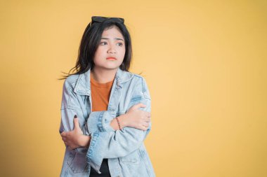 Genç bir kadın üşümüş, iki eli de kollarında.