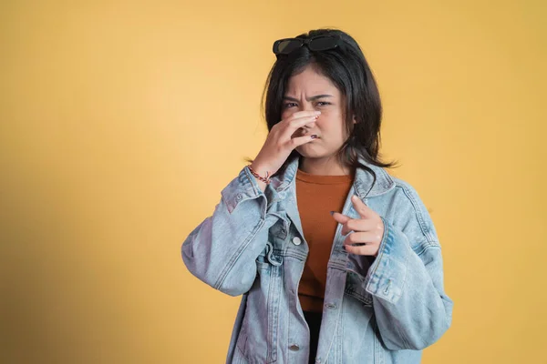 Jovem mulher asiática cobrindo o nariz com o dedo quando mau cheiro — Fotografia de Stock