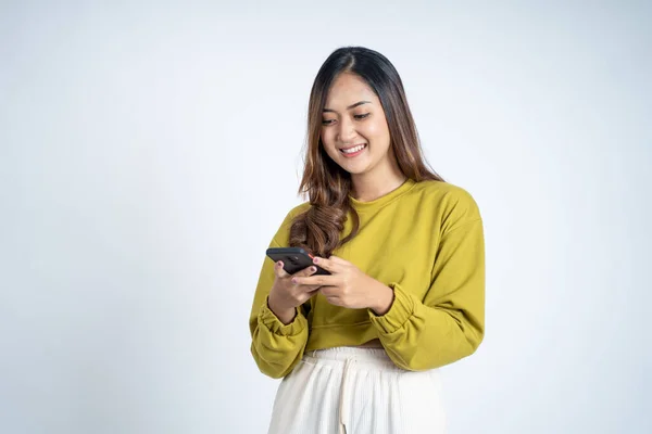 Молодая азиатка с помощью мобильного телефона набирает смс сообщение — стоковое фото