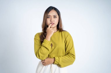 Genç Asyalı kadın ısırık parmağı hareketleriyle bir şeyler düşünüyor.