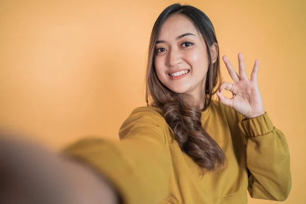 Fiatal nő mosolyog, amikor szelfi jó kézmozdulattal — Stock Fotó
