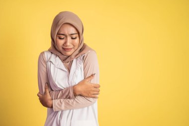 Müslüman kadın üşüyor, iki eli de vücuduna sarılıyor.