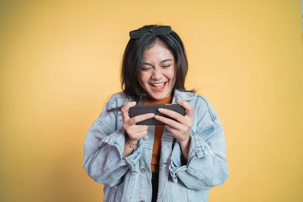 Aziatische meisje lachen tijdens het spelen spel met behulp van mobiele telefoon — Stockfoto