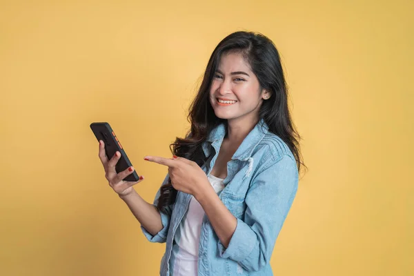 Mladá žena se usmívá ukazováčkem pomocí mobilního telefonu — Stock fotografie