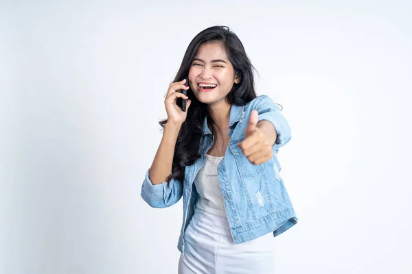 Giovane donna asiatica che fa una chiamata utilizzando un telefono cellulare con i pollici in su — Foto Stock
