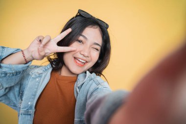 V işaretli cep telefonu kamerası kullanan genç bir kadın selfie 'si