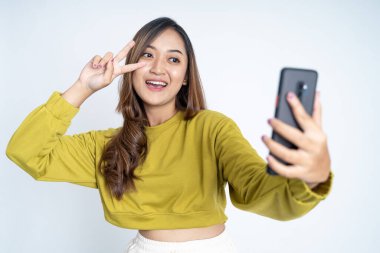 Genç bir kadın barış hareketiyle selfie çekiyor.