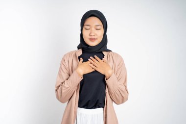 Müslüman kadın, rahatlamış hissederken göğsünü tutarak gözlerini kapatıyor.