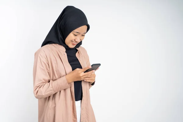 Ασιάτισσα με χιτζάμπ χαμογελά ενώ χρησιμοποιεί κινητό τηλέφωνο — Φωτογραφία Αρχείου