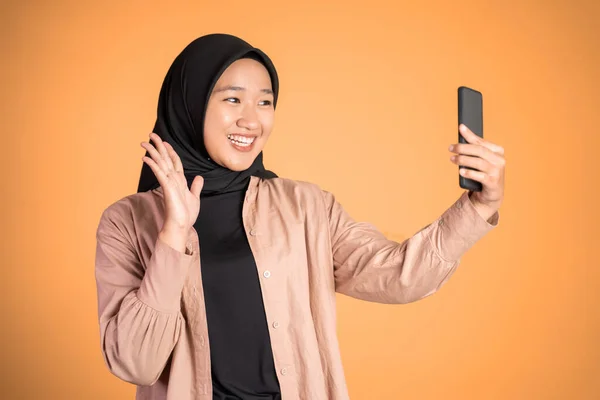 Женщина в хиджабе держит смартфон для селфи — стоковое фото