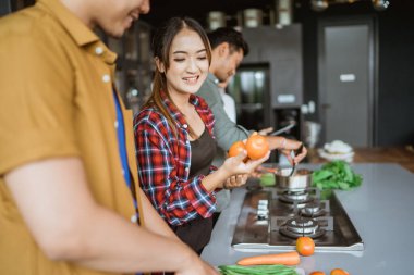 Mutfakta birlikte yemek pişiren bir grup arkadaşın fotoğrafı.