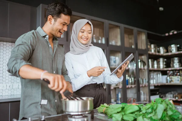 Muszlim pár főzés együtt a konyhában, miközben nézd meg a videót — Stock Fotó