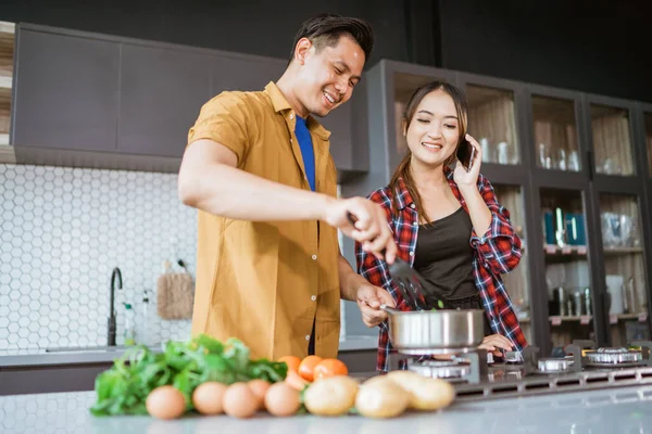 Молода пара просить рецепт, поки вони готують вдома разом — стокове фото