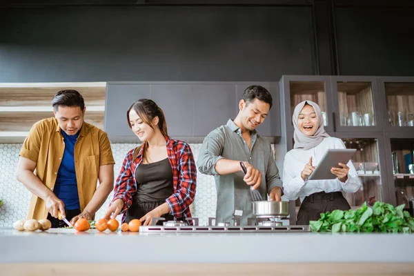 Vriend koken samen in de keuken terwijl kijken naar online cursus van tablet pc — Stockfoto