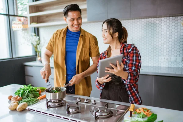 Pareja aprendiendo a cocinar algo de comida del video de internet. —  Fotos de Stock