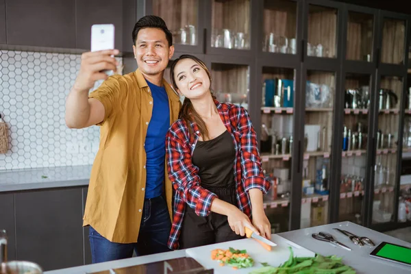 Asiático casal tomando selfie enquanto cozinhar juntos na cozinha — Fotografia de Stock