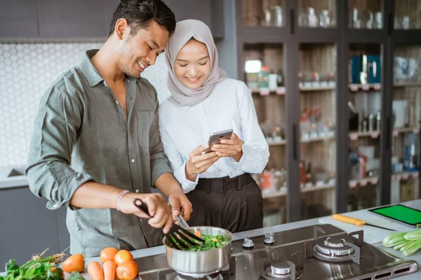 Moslim paar koken samen in de keuken terwijl kijken naar video — Stockfoto