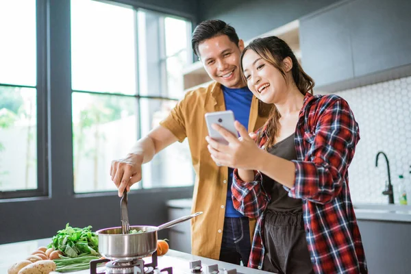 Casal jovem preparando comida deliciosa juntos em casa. — Fotografia de Stock