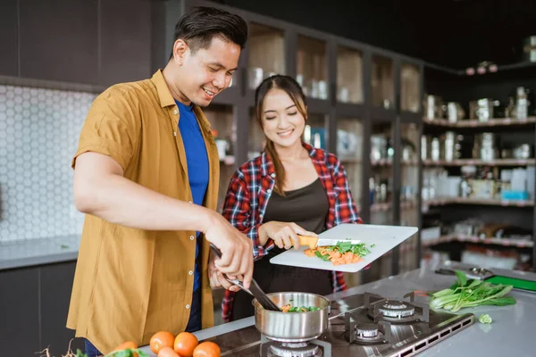 Young couple preparing delicious food together at home. — Stock Photo, Image