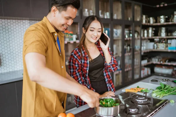 Young couple asking for some recipe while they cook at home together — Stock Photo, Image