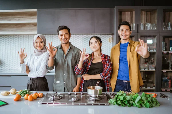 Друзі готуються готувати на кухні разом показуючи великий палець вгору — стокове фото
