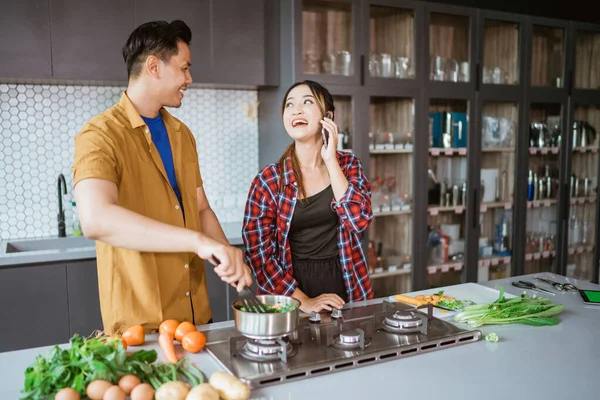 Casal jovem pedindo alguma receita enquanto eles cozinham em casa juntos — Fotografia de Stock