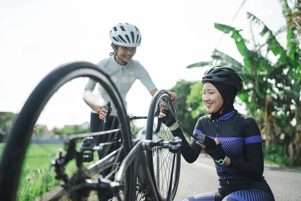 Asijské muslim kolo cyklista čerpadlo její píchlé pneumatiky pomocí elektrického čerpadla — Stock fotografie