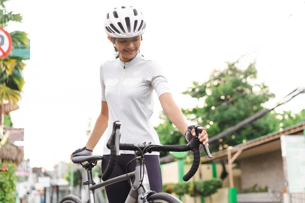 Atractiva joven ciclista femenina preparándose para montar su bicicleta — Foto de Stock