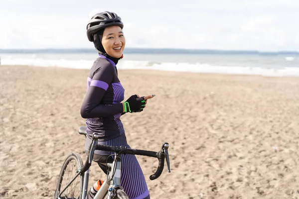 自転車に乗ってスマートフォンを見ている女性サイクリストは — ストック写真