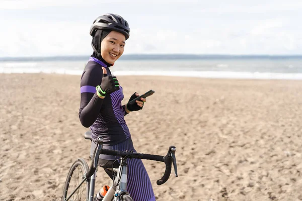 Ciclista musulmán con hiyab mostrando el pulgar hacia arriba mientras monta — Foto de Stock