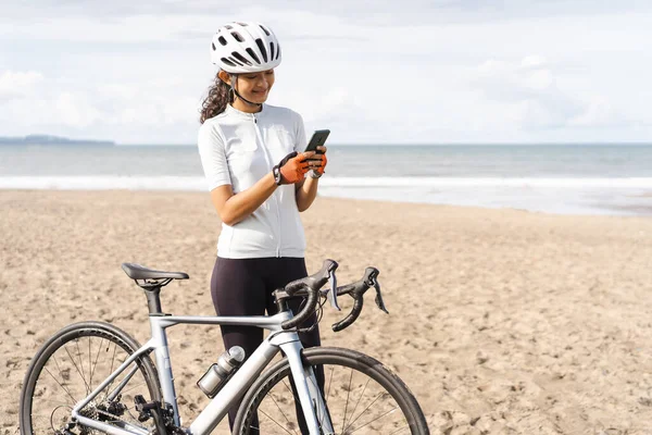 Ciclista femenina mirando su teléfono inteligente después de montar en bicicleta — Foto de Stock