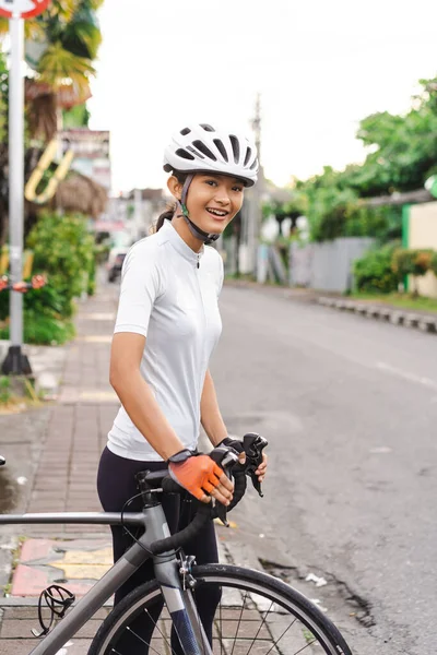 Atractiva joven ciclista femenina preparándose para montar su bicicleta — Foto de Stock