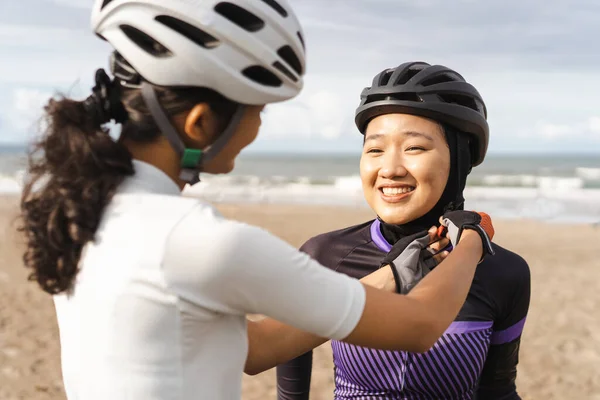 Žena pomáhá její muslimský přítel upevnit její cyklistické helmy — Stock fotografie