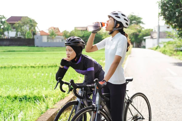 自転車の女性は道路脇に水を1本持っていて — ストック写真
