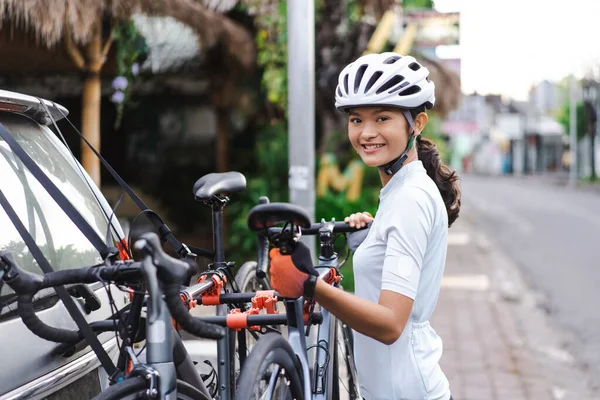 Female cyclist unloading her road bicycle on a rack in the back of her car — Stock Photo, Image