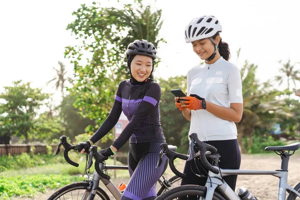 Žena cyklistka při pohledu na její smartphone po jízdě na kole — Stock fotografie