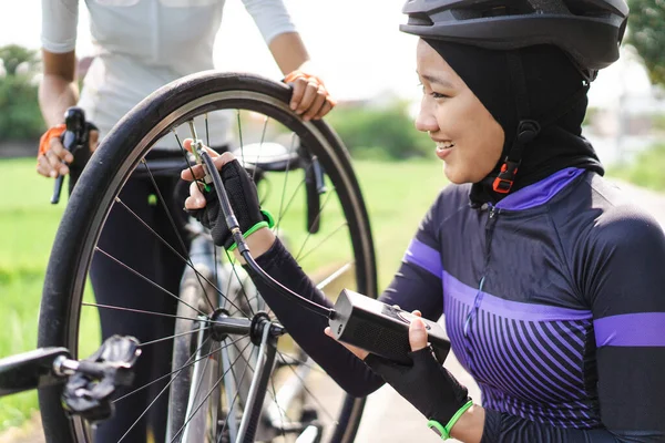 アジアのイスラム教徒の自転車サイクリストは電気ポンプを使用して彼女のフラットタイヤをポンプ — ストック写真