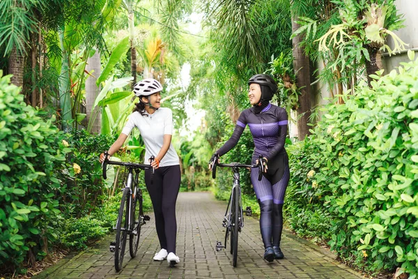 Dos ciclistas musulmanas empujan su bicicleta y hablan —  Fotos de Stock
