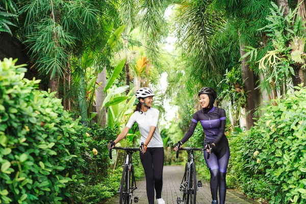 Две мусульманки-велосипедистки толкают свой велосипед и разговаривают — стоковое фото