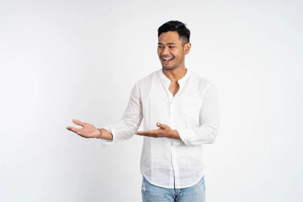Asijský mladý muž s oběma rukama představuje něco — Stock fotografie
