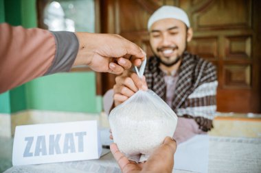 man giving a rice as a food donation for zakat during eid mubarak clipart