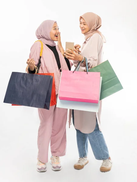 Junge muslimische Freundin benutzt Smartphone und hält Einkaufstasche — Stockfoto
