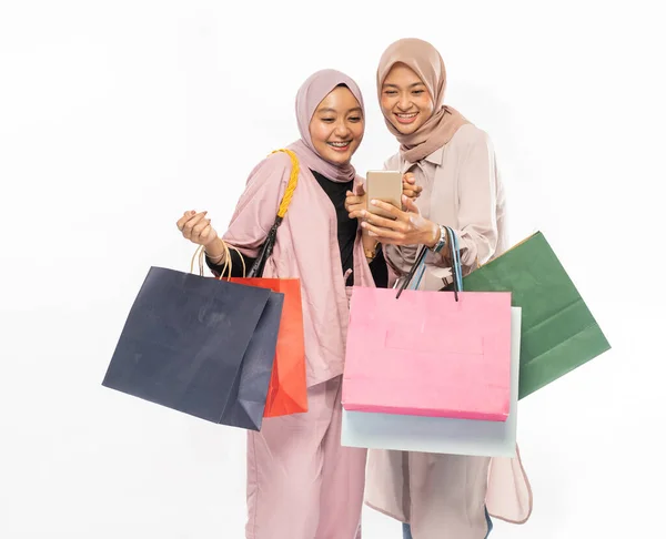 Musulmán joven amigo utilizando el teléfono inteligente y la celebración de la bolsa de compras —  Fotos de Stock