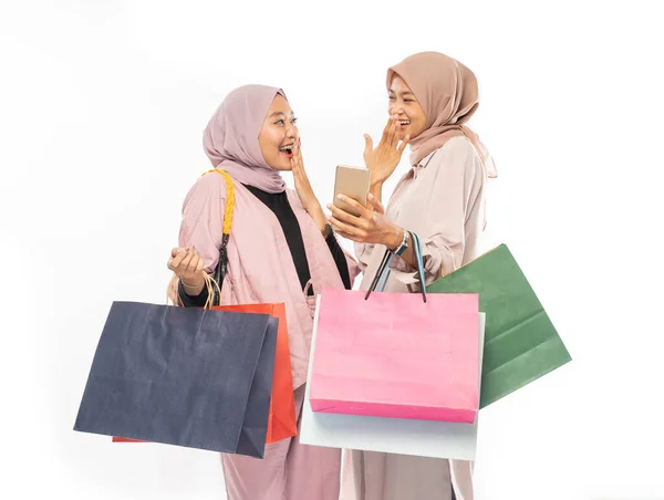 Jovem amigo muçulmano usando telefone inteligente e segurando saco de compras — Fotografia de Stock