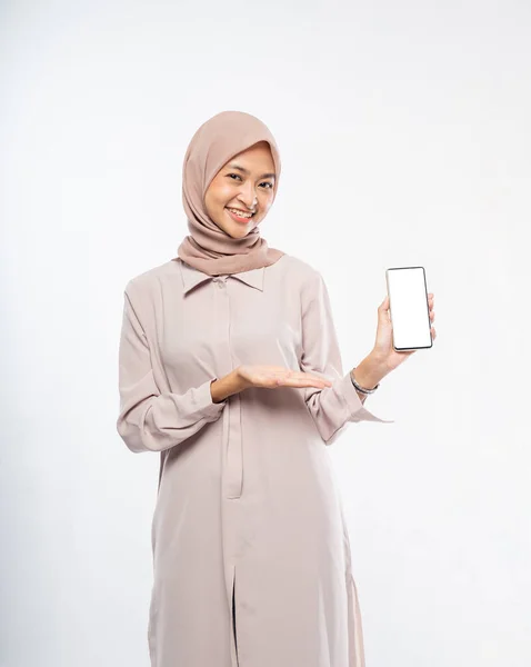 Frau im Hidschab lächelt, während sie ein Handy benutzt, das der Kamera den leeren Bildschirm zeigt — Stockfoto