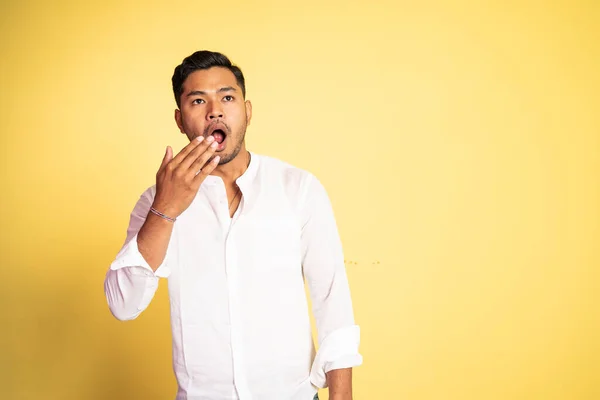 Asian young man yawning with hand covering mouth — Stock Photo, Image