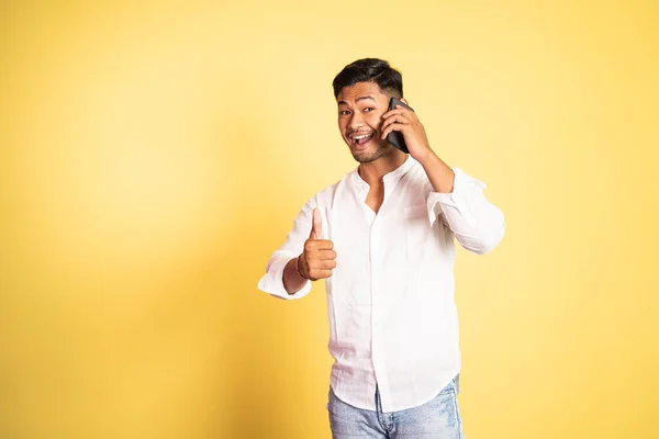 Aufgeregter junger Mann im weißen Hemd ruft mit erhobenem Daumen — Stockfoto