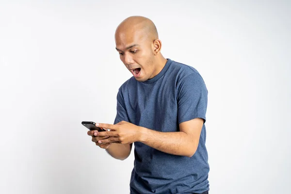 Skallig asiatisk man chockad när du tittar på smartphone — Stockfoto